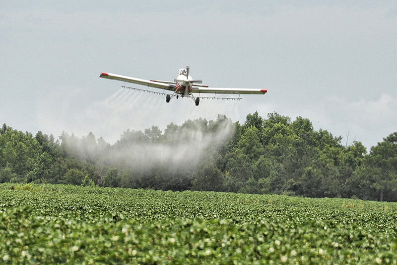 Plane spraying pesticide on field