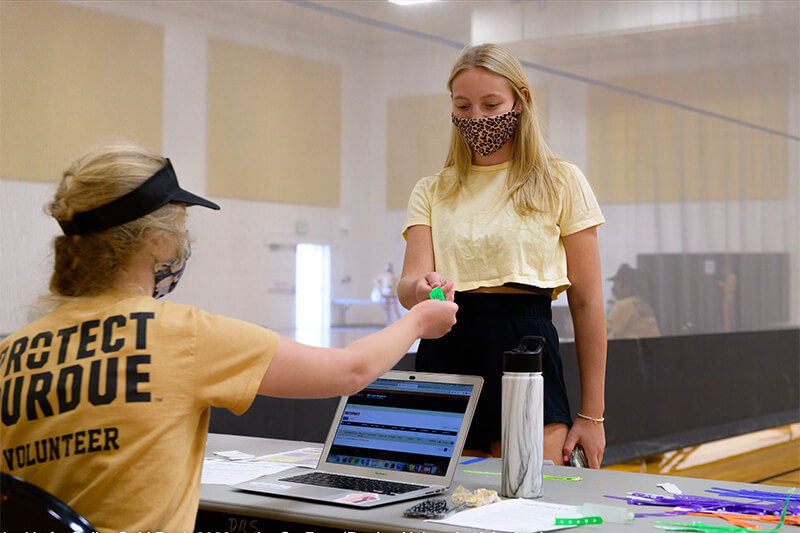 student check-in at table, masks worn