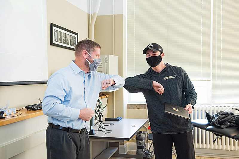 Hayden White exchanges an arm bump with clinical professor Scott Lawrance