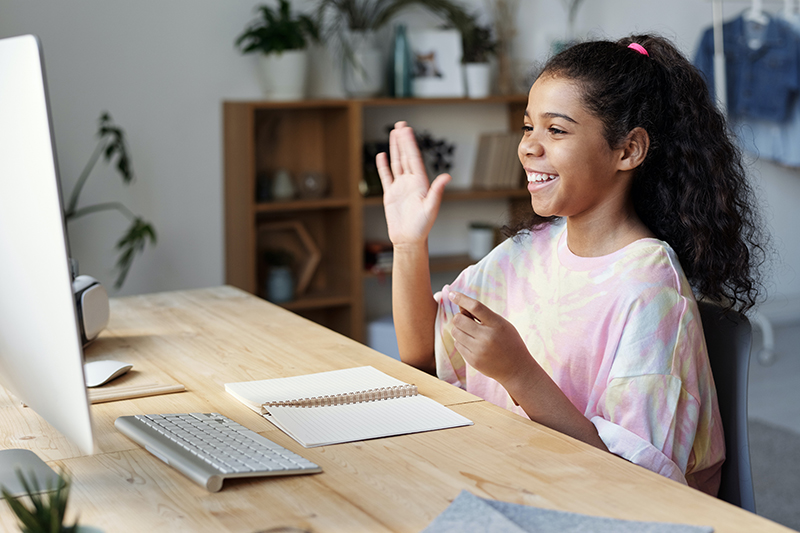 Child raising hand and looking at computer