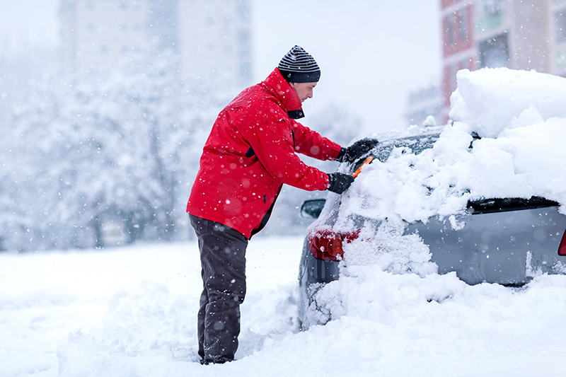 Man cleaning snow off car