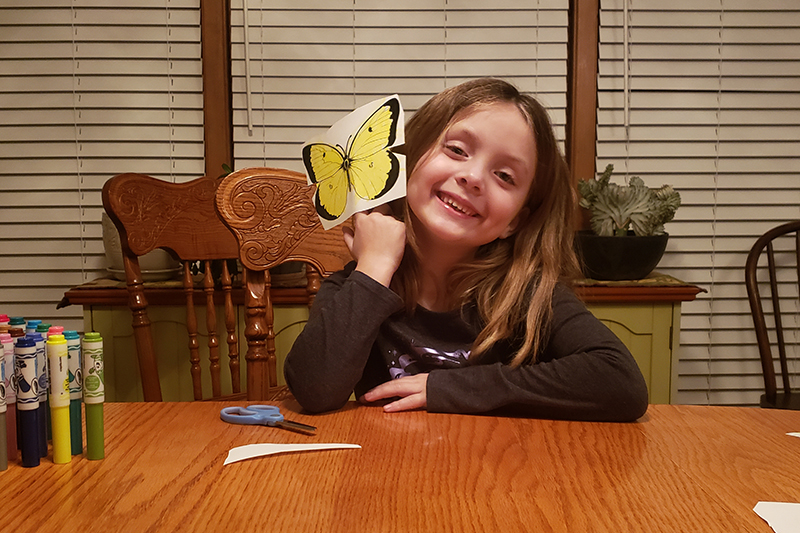child with craft items at home dining table