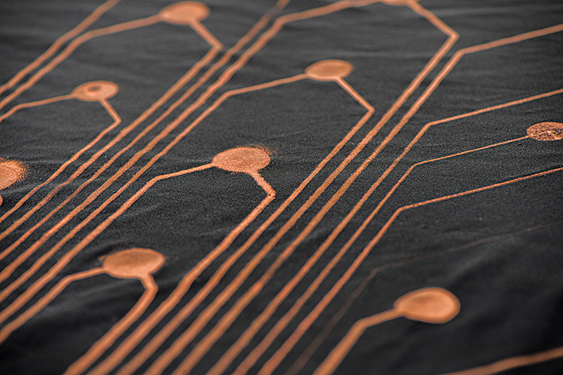 The black fabric has gold-colored patterns of sensors embedded into it