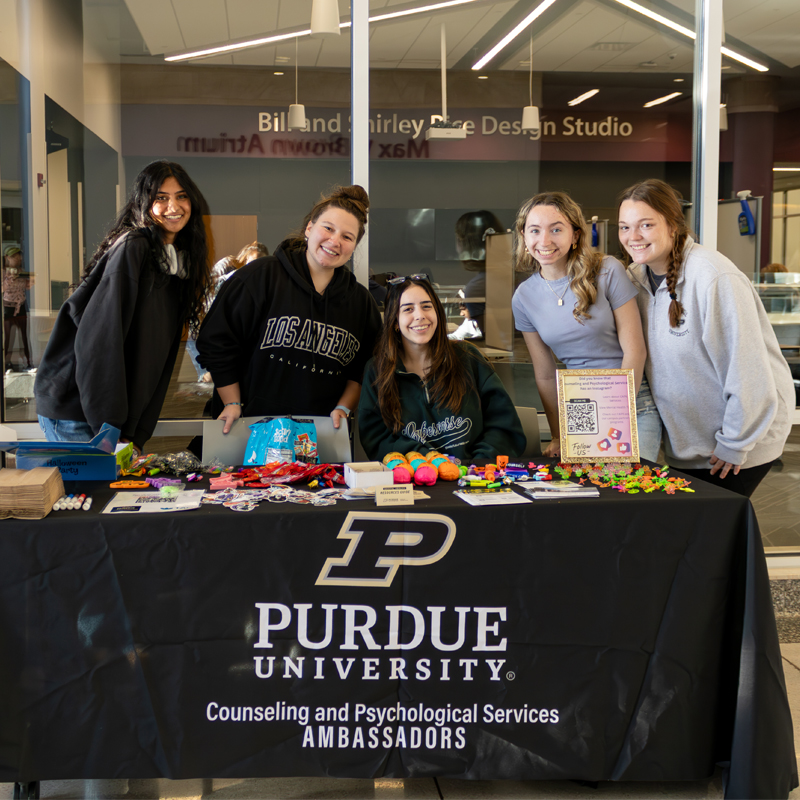 Caps ambassadors standing behind a tabling event called Goodies and Gratitude.