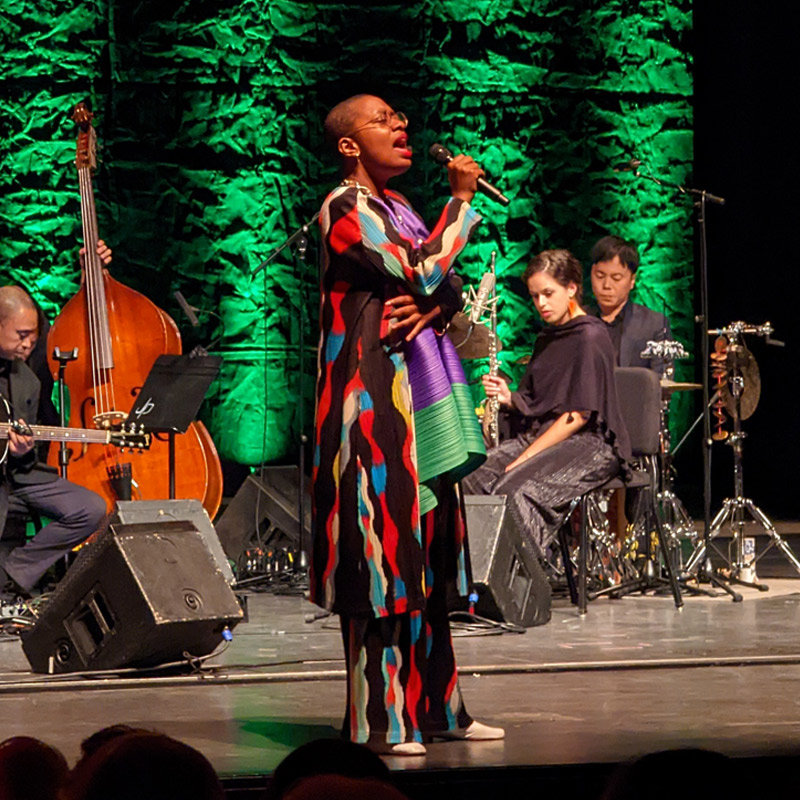 A singer on stage in front of a band during Convos PXL concert .