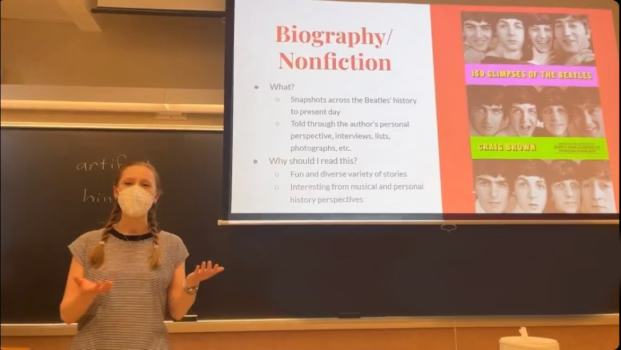 Photo of Student English Association member reading slides on why someone should read Biography and Nonfiction books