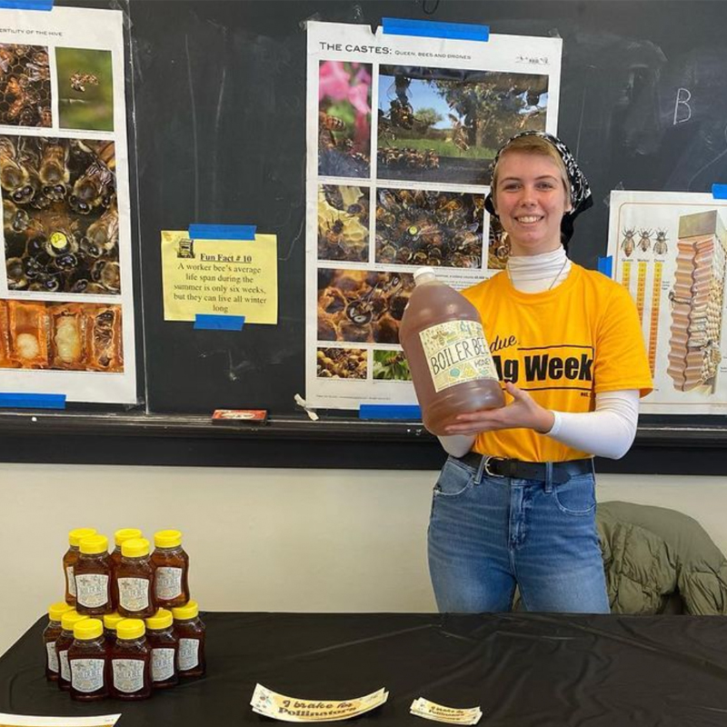 A photo of student holding a jar of honey made by the Purdue Beekeeping Club