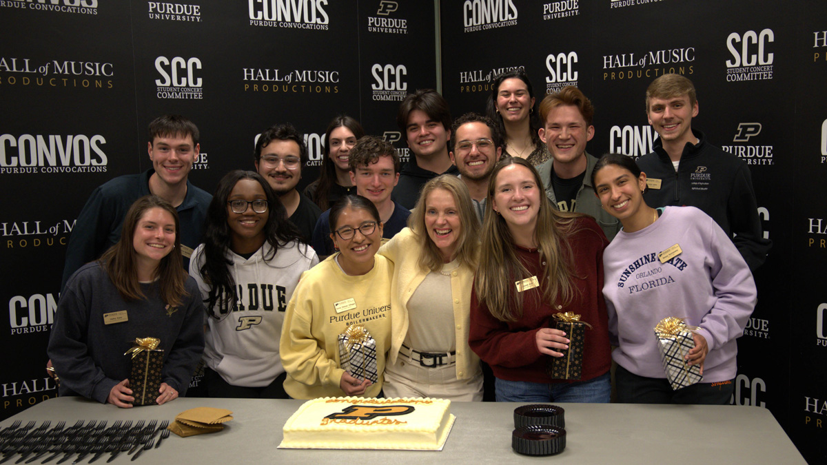 Purdue students with Beth McCuskey, smiling around a Purdue-themed cake