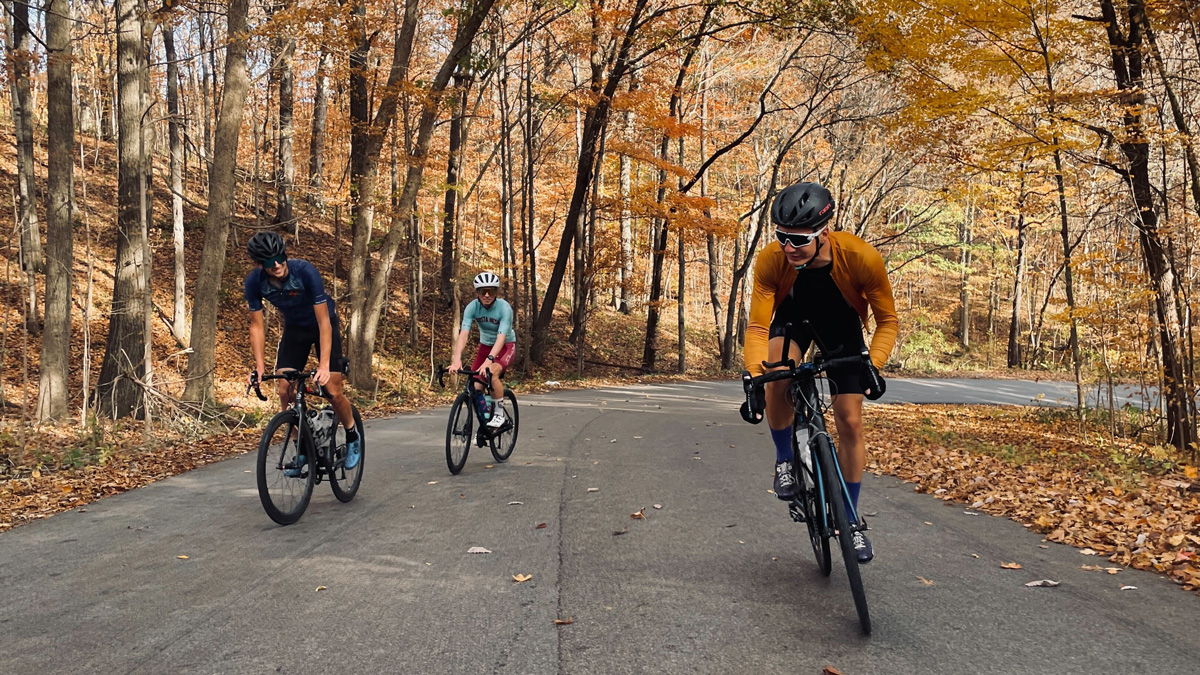 Purdue cyclists riding down a path on an autumn day.