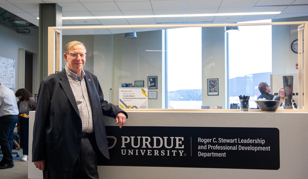 Roger C. Stewart standing in front of a sign with the new name of the department, the Roger C. Stewart Leadership and Professional Development Department