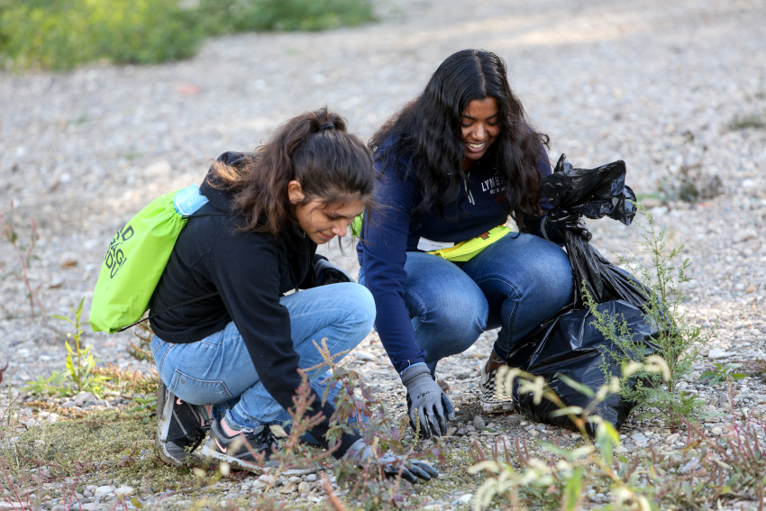 Two students picking up litter along the Wabash River