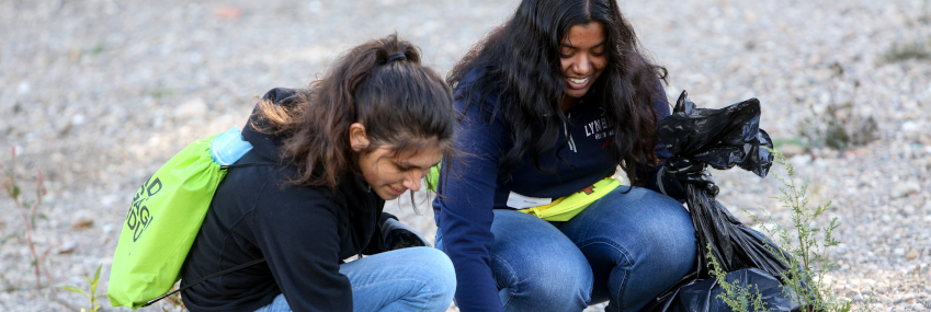 Two students picking up litter along the Wabash River