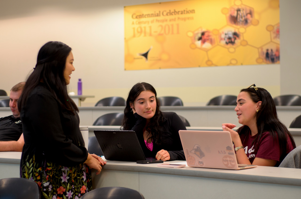 A presenter talking with two workshop attendees