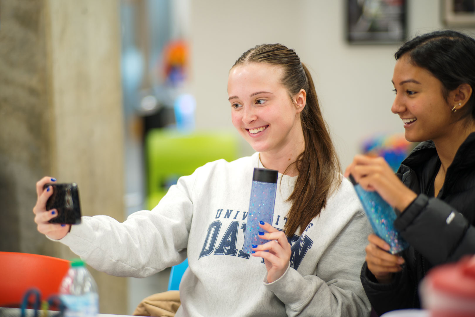 Two students take a selfie with a cell phone.