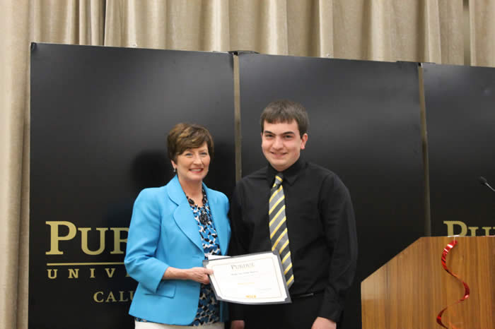 Photograph of 2014 award recipient Matthew Meier receiving award certificate from Peggy S. Gerard